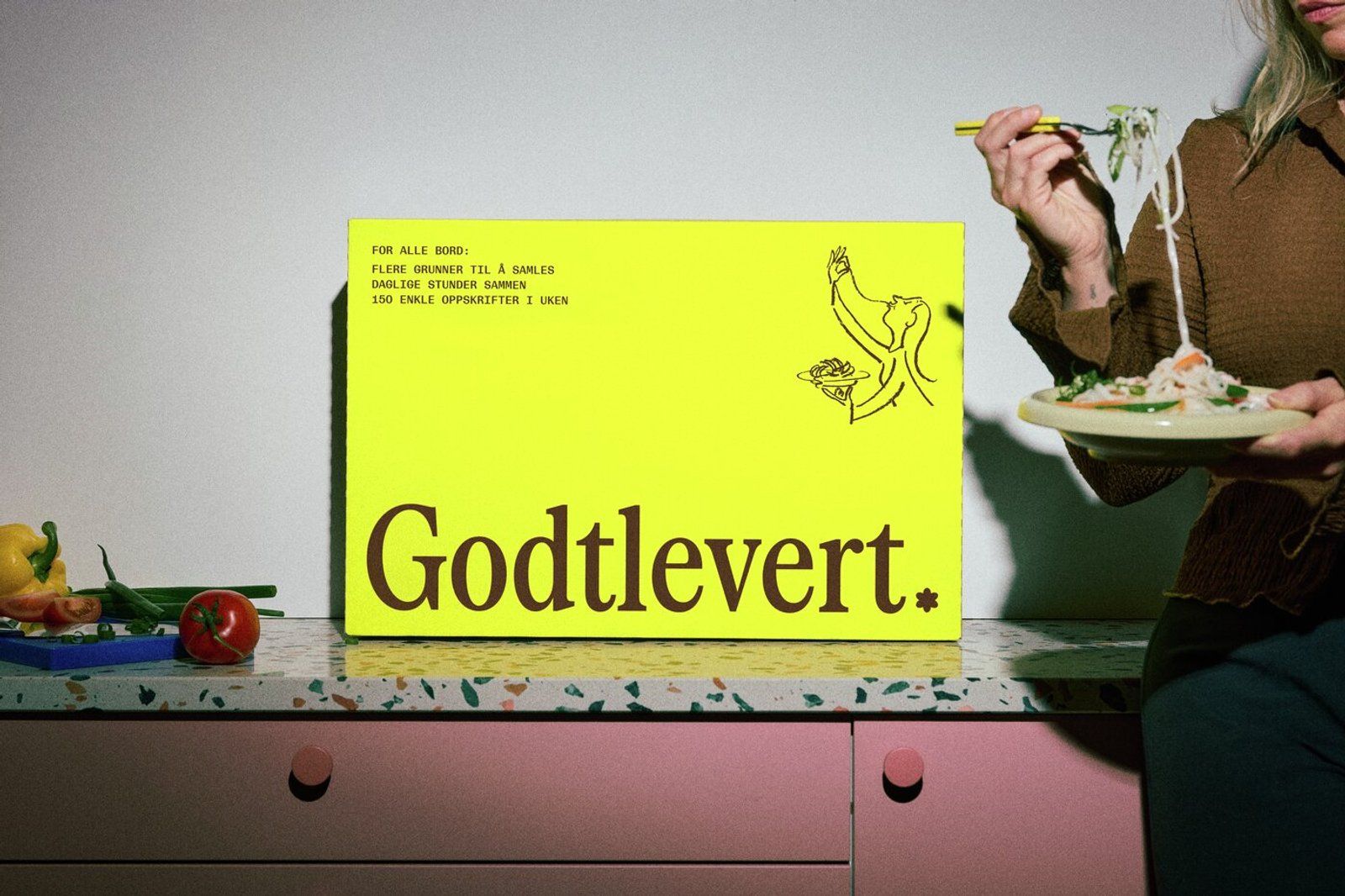 Godtlevert-kassen på kjøkkenbenken mens en person spiser pasta ved siden av