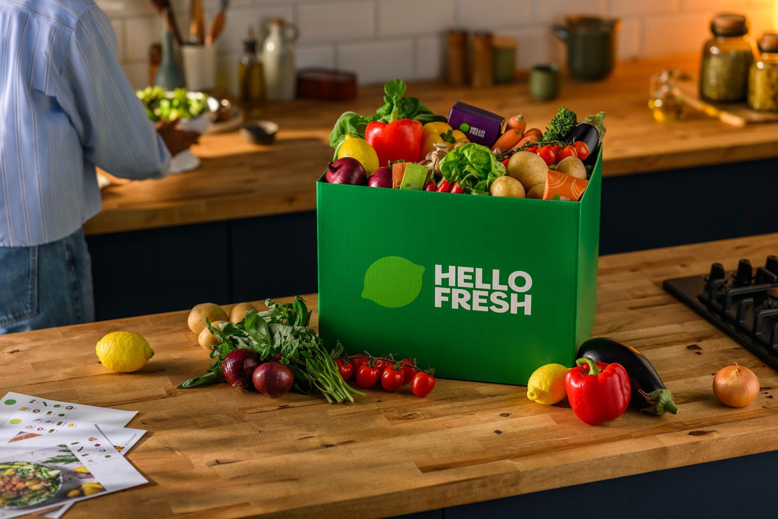 Den grønne HelloFresh-kassen full av grønnsaker og råvarer på en kjøkkenbenk